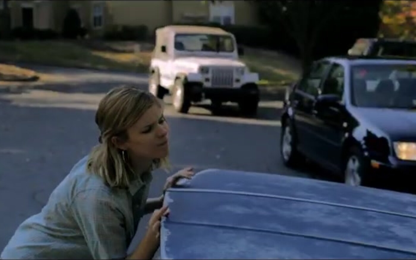 Kate Mara leans over a car hood on a suburban street in Captive