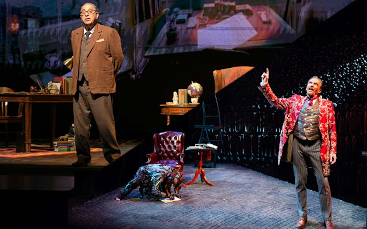Max McLean as C.S. Lewis at a desk shares the stage with Screwtape in a red coat and Toadpipe on the floor